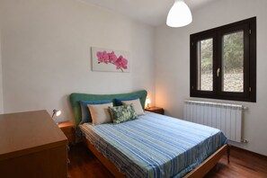 A bedroom with a bed, a nightstand, a lamp, a radiator, and a window with a view of greenery. - Villa in Monterosso Almo with 3 bedrooms sleeps 8 (Monterosso Almo)