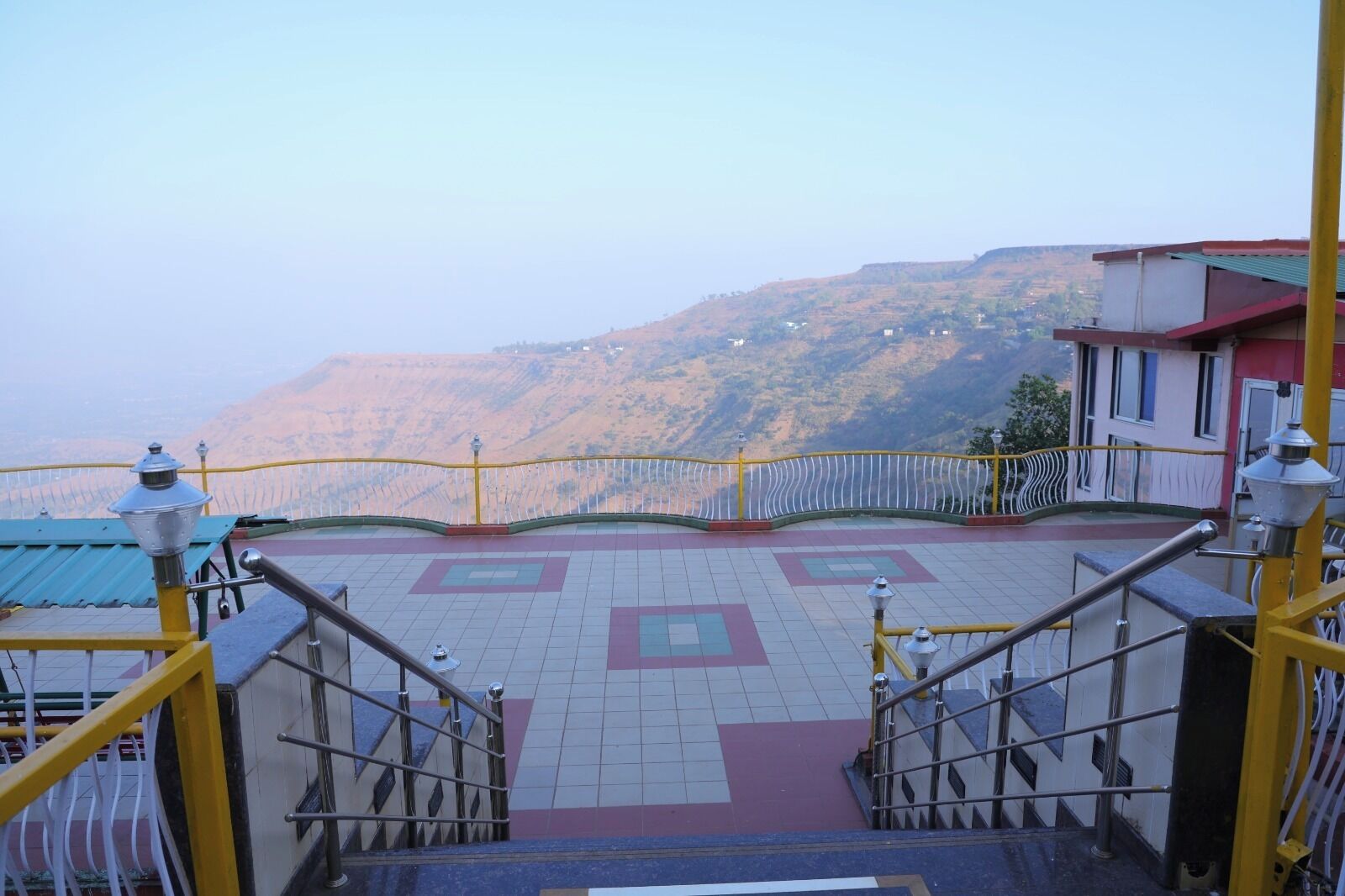 A staircase leading to a terrace with a view of a mountainous landscape.
