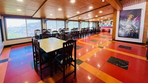 A dining area with wooden ceiling, large windows, and a colorful floor.