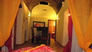 Una stanza con un letto, una scrivania e una sedia, caratterizzata da un arco in pietra e tende.