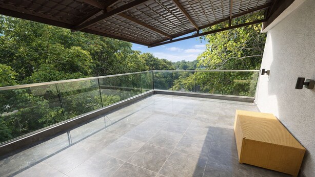A spacious balcony with a glass railing, a tiled floor, and a wicker bench. - Taaffeite Hotel And Resorts (Pune)