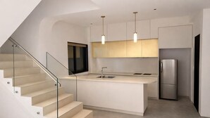 A modern kitchen with a central island, stainless steel appliances, and a glass staircase. - Taaffeite Hotel And Resorts (Pune)