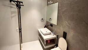 A modern bathroom with a white sink, a toilet, a large mirror, and a towel rack. - Taaffeite Hotel And Resorts (Pune)