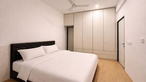 A bedroom with a bed, a ceiling fan, and a wardrobe. - Taaffeite Hotel And Resorts (Pune)