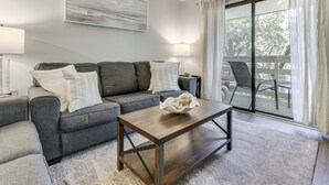 Ein Wohnzimmer mit einer Couch, einem Couchtisch und Blick durch eine Glastür.