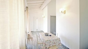 A room with a table set for dining, a white door, and a light fixture on the wall. - Villa Artemis apartment 1 (Capoliveri isola d'Elba)