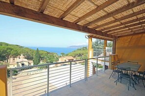 A balcony with a view of the sea, a table with chairs, and a thatched roof. - Villa Artemis apartment 2 (Capoliveri isola d'Elba)