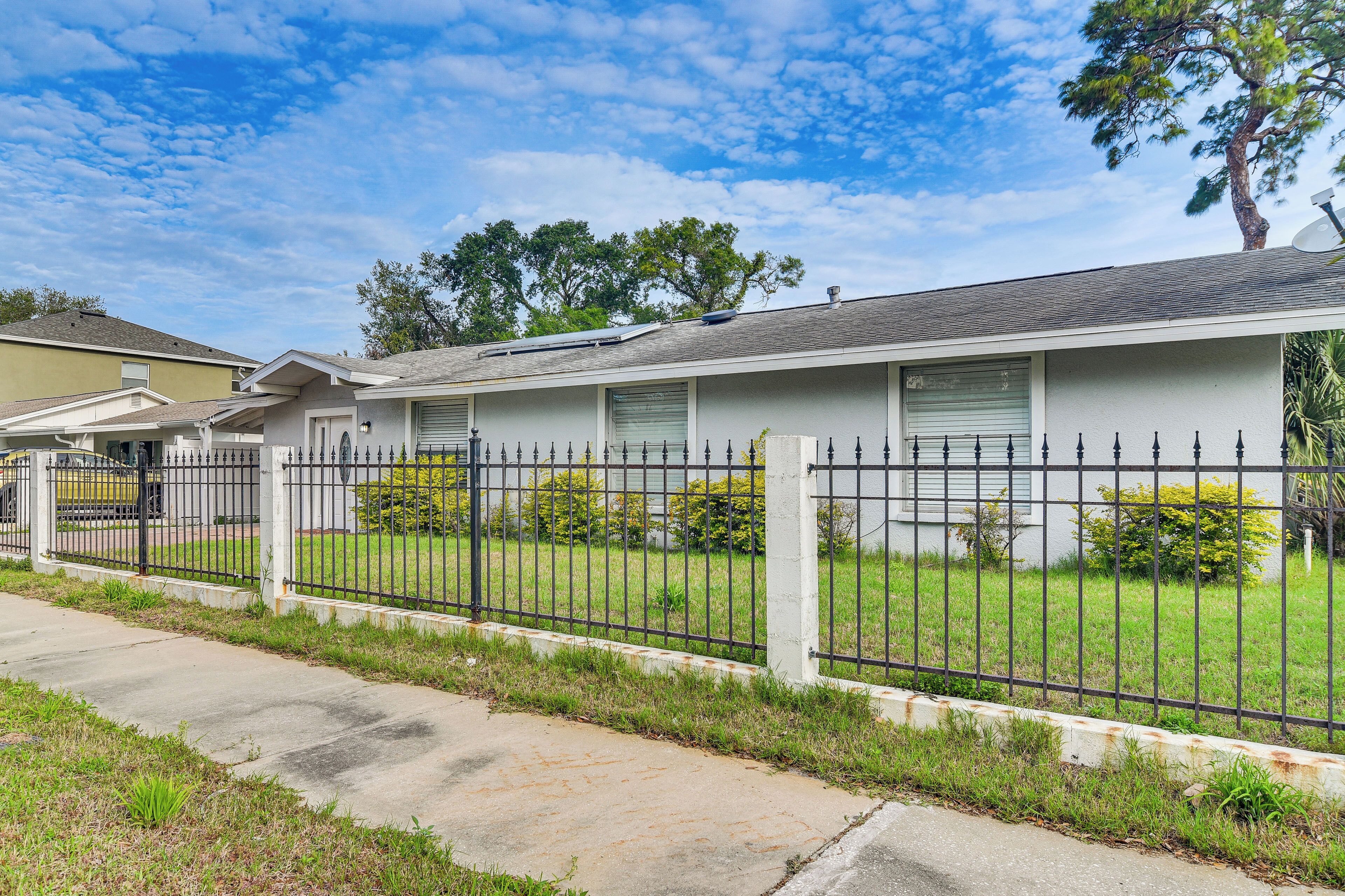 A residential house with a fenced yard, a driveway, and a satellite dish.