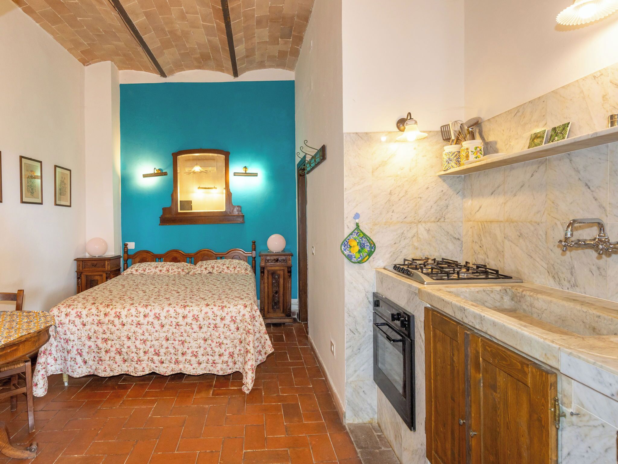 Ein Schlafzimmer mit Bett, Nachttisch, Schminktisch und Wandgasherd.