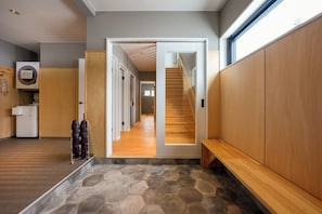 Un couloir avec un banc en bois, un escalier et une vue sur une autre pièce.