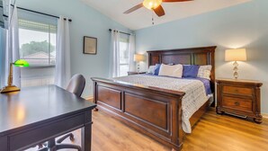 Ein Schlafzimmer mit Bett, Schreibtisch, Stuhl, Nachttischen und Deckenventilator.