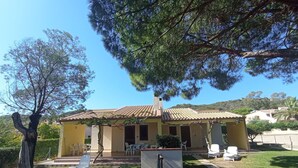 Una casa con tetto in tegole, un portico con sedie e un prato.