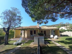 Ein Haus mit einem Ziegeldach, einer Veranda mit Stühlen und einem Rasen.