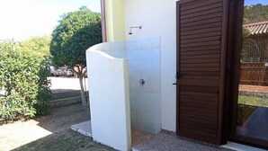 Un edificio con una zona esterna coperta, un'entrata e un piccolo giardino.