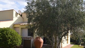 Una casa con giardino, un vaso di terracotta di grandi dimensioni e un'antenna parabolica.