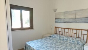 Una camera da letto con un letto, una finestra, un quadro appeso al muro e un comodino.