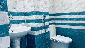 Egy fürdőszoba, amelyben mosdókagyló, WC és zuhanyzó található.