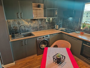 Una cocina compacta con lavadora, un lavamanos y un pequeño comedor con mesa.