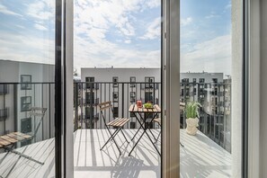 A balcony with a table, chairs, a potted plant, and a view of adjacent buildings. - Lumina Apart near Orientarium ZOO Łódź (Łódź)