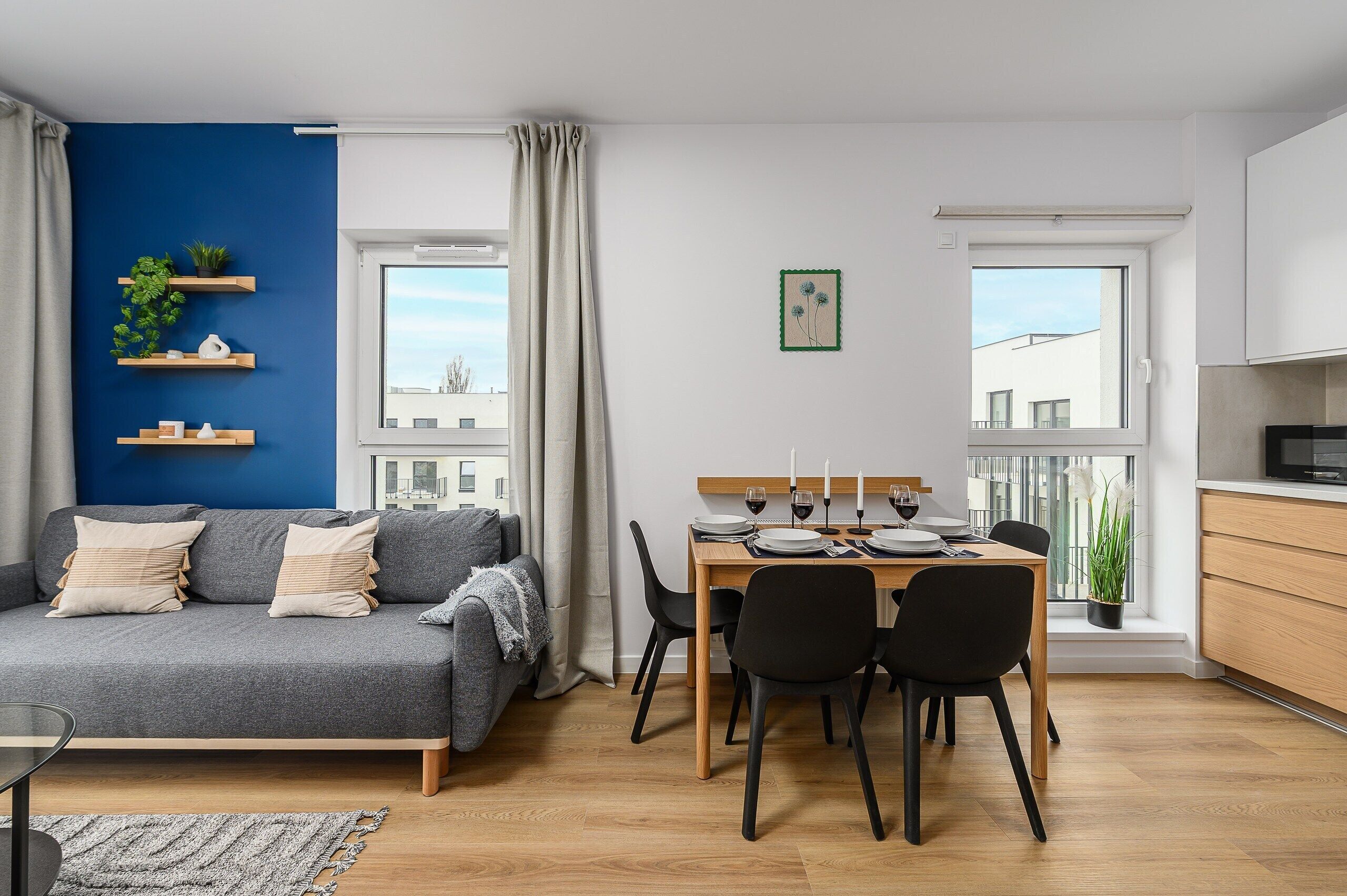 A modern apartment with a dining area, a sofa, and a kitchen.