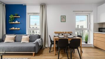 A modern apartment with a dining area, a sofa, and a kitchen.
