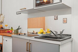 Eine moderne Küche mit eingebautem Backofen, einer doppelten Spüle und einer Wandpaneele aus Holz.