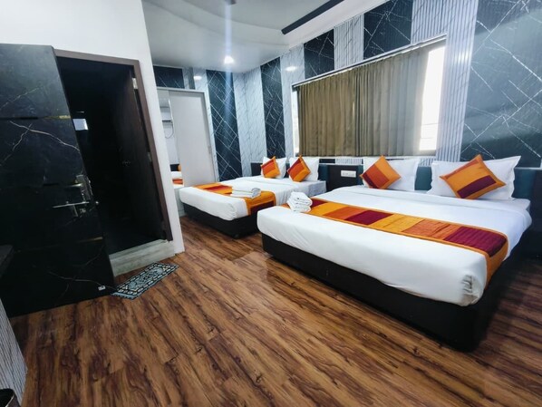 A hotel room with two beds, a wooden floor, a marble wall, and a window with curtains.
