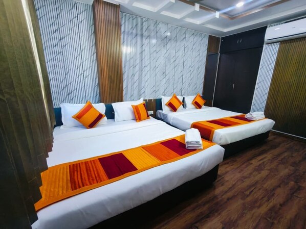 Habitación de hotel con dos camas, suelo de madera y pared a rayas.