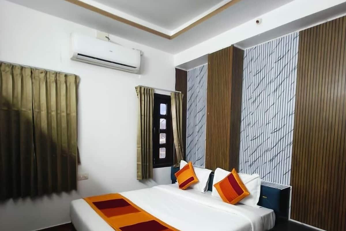 Habitación de hotel con cama, ventilador de techo, aire acondicionado y ventana con cortinas.