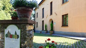 Un cortile con una targa in pietra, piante in vaso e un edificio con finestre ad arco.