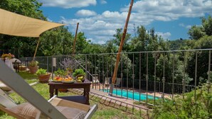 Area piscina con tavolo, sedie e zona ombreggiata.
