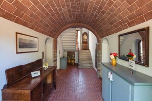 A hallway with a brick ceiling, a wooden bench, a reception desk with a mirror, and a staircase leading to an upper floor. - Leccio, bright apartment with view over the valley and with swimming pool (Sassetta (LI))