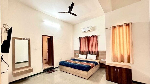 Une chambre d’hôtel équipée d’un lit, d’un ventilateur de plafond, d’une armoire, d’un miroir et d’un espace douche.