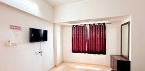 Une chambre d’hôtel dotée d’un téléviseur à écran plat fixé au mur, d’une enseigne indiquant qu’il s’agit d’un hôtel de luxe, d’un rideau de douche et d’un miroir.