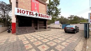 Un hôtel appelé « HOTEL REGENCY » affiche une enseigne indiquant qu’il propose des chambres climatisées, une connexion Wi-Fi gratuite et de l’eau chaude 24 heures sur 24.