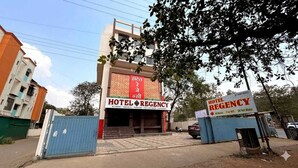 Un hôtel avec une enseigne, une entrée fermée par un portail et une façade.