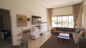 Un salon moderne comprenant un canapé, une table basse, un téléviseur et des meubles de rangement.