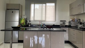 Une cuisine moderne dotée d’un îlot central, d’appareils électroménagers en acier inoxydable et d’une fenêtre laissant entrer la lumière naturelle.