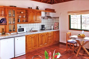 A kitchen with wooden cabinets, a microwave, a coffee maker, and a dining area with a table and chairs. - Independent holiday home in La Palma with a community pool (Los Llanos de Aridane)
