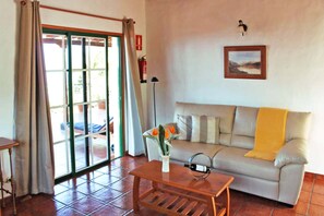 A living room with a sofa, a coffee table, a vase with flowers, a wine bottle, a lamp, a painting, and a sliding glass door. - Independent holiday home in La Palma with a community pool (Los Llanos de Aridane)