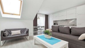Ein modernes Wohnzimmer mit Sofa, Couchtisch und einem Essbereich mit Stühlen und Tisch.