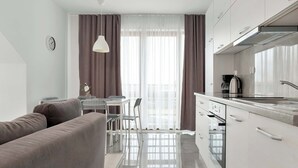 Eine moderne Küche mit Einbauofen, eine Essecke mit Tisch und Stühlen sowie ein Wohnbereich mit einer Couch.