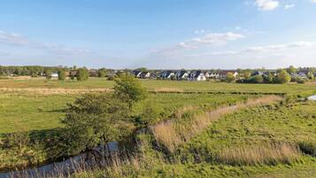 Ländliche Landschaft mit einer Reihe von Häusern, einem Bach und offenen Feldern.