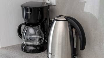 Una cafetera negra y un hervidor de acero inoxidable sobre una encimera de cocina.