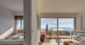 A bedroom with a bed, a nightstand, and a window with a view of the sea. - Villa Karima Sunset & Sea Views, Sea & Sunset View Villa Karima | Private Jacuzzi (Argolida)