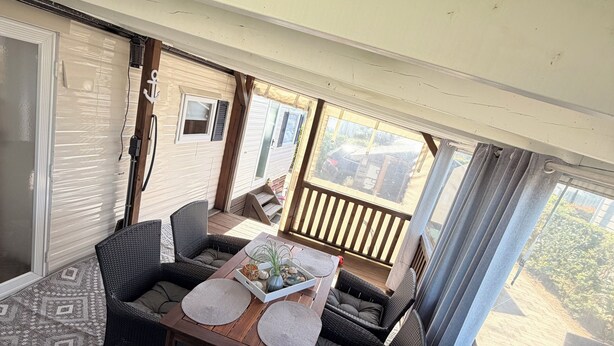 A covered patio area with a table set for two, surrounded by wicker furniture.