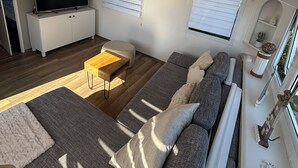 A modern RV interior with a sofa, TV, and wooden coffee table.