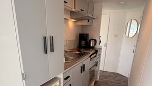 A narrow kitchen with white cabinets, a built-in oven, and a coffee maker.