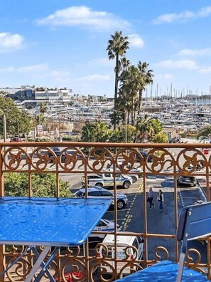 A balcony with a view of a marina, palm trees, and parked cars. - Cannes Port | Suite 1 | Balcon vue Palais (Cannes)