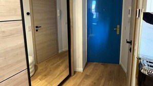 A hallway with wooden flooring, a blue door, and a mirror reflecting a wardrobe. - Cannes Port | Suite 4 | 2 min Palais (Cannes)